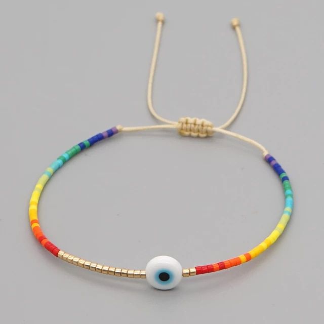 a bracelet with an evil eye and multicolored bead on the end, sitting on a gray surface