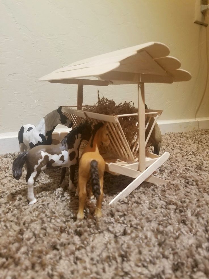 several toy horses are standing in front of a table with an umbrella on top of it