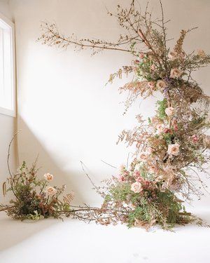 flowers are arranged on the floor in front of a white wall with a window behind them