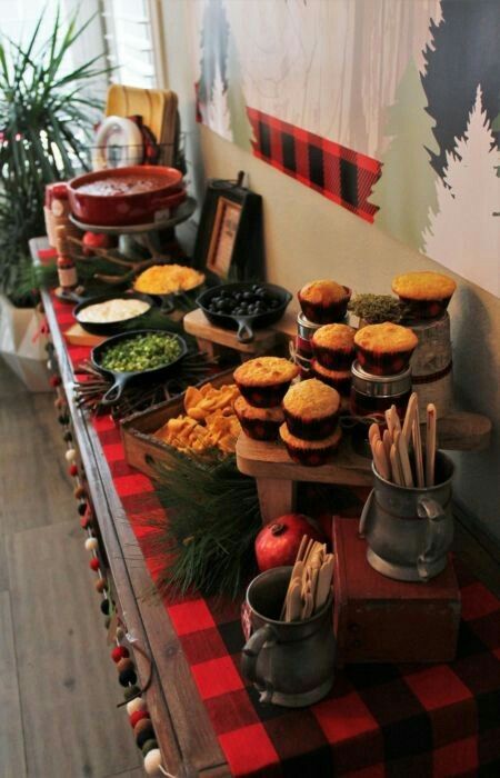 an assortment of food is displayed on a long table with red and black checkered cloth