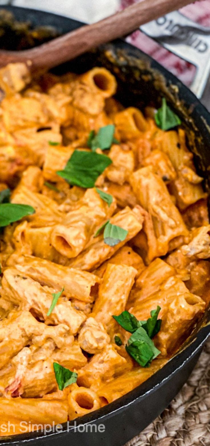 a skillet filled with pasta and sauce on top of a table next to money