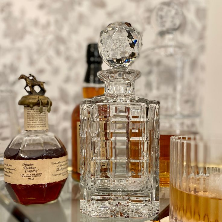 a bottle of liquor sitting on top of a table next to two glasses and a decanter