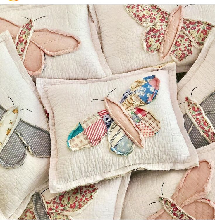 several pillows with different designs on them and one has a butterfly appliqued on it