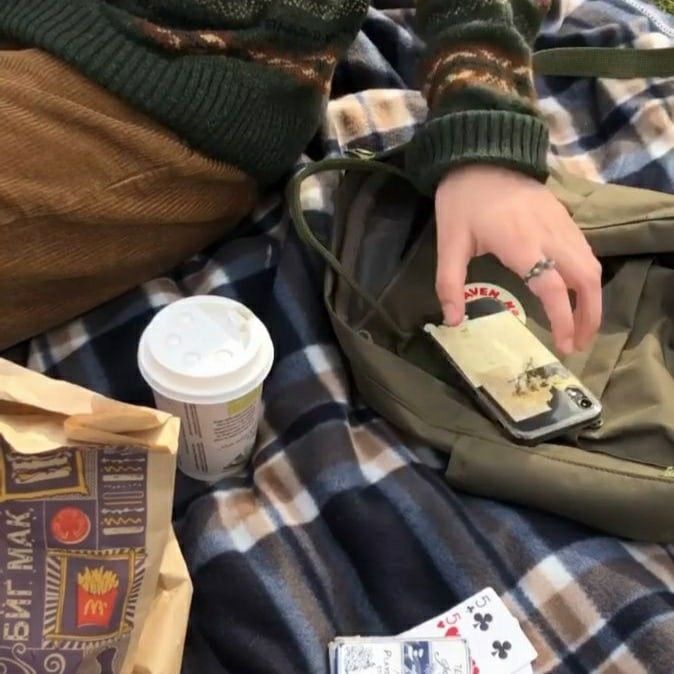 a person laying on a blanket with a cell phone in their pocket and some coffee