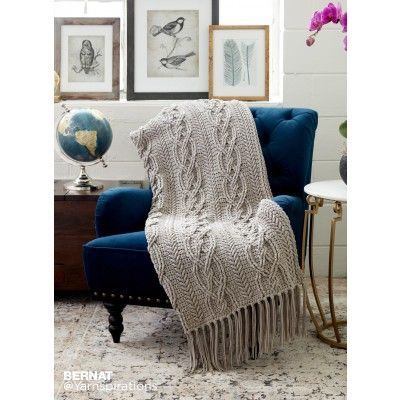 a blue chair with a blanket on top of it next to a table and flowers