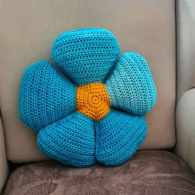 a crocheted blue flower sitting on top of a couch