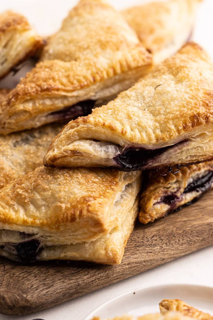 several pastries stacked on top of each other next to a white plate with blueberries