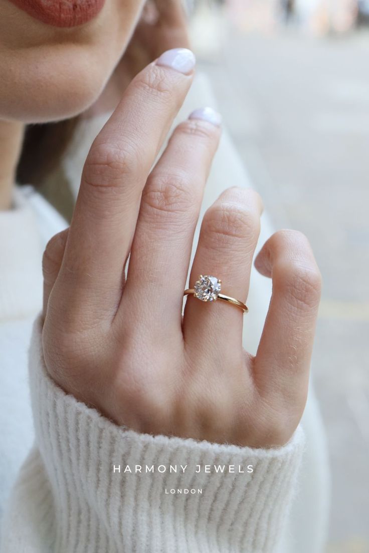 a close up of a person's hand with a diamond ring on their finger