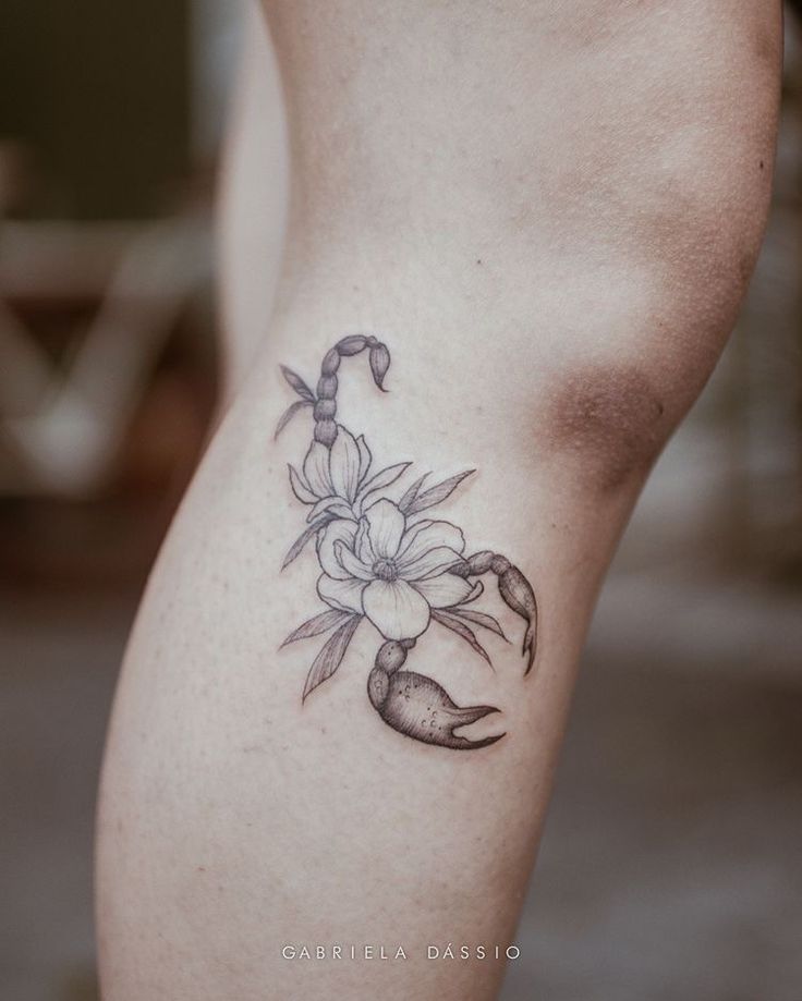 a woman's lower leg with a flower tattoo on her left thigh and an anchor in the middle