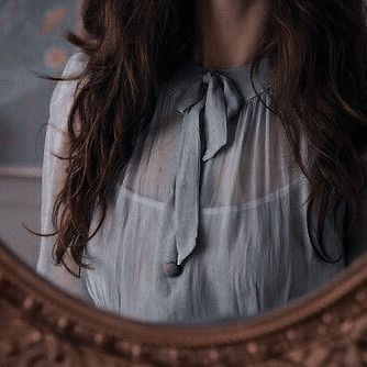 a woman is standing in front of a mirror with her hair blowing in the wind