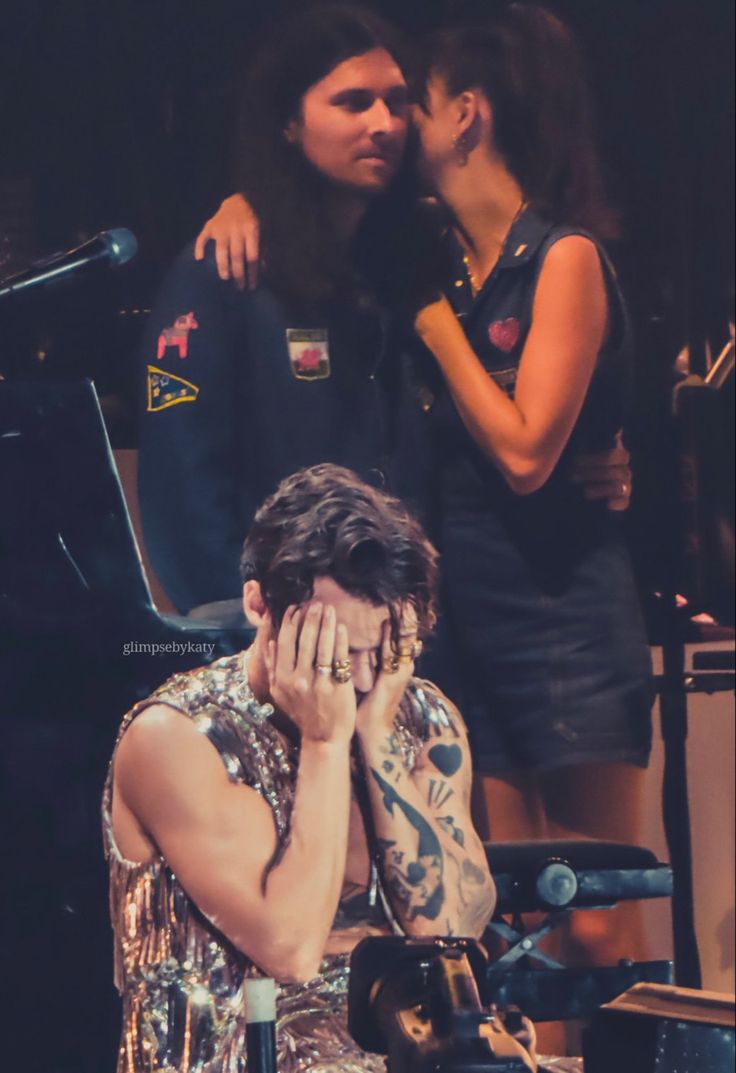 a man covering his face while sitting in front of a piano