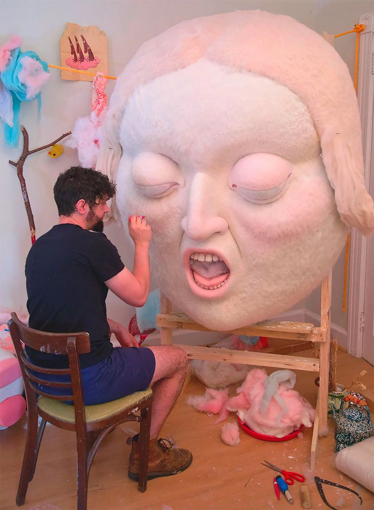 a man sitting in front of a large white head on top of a wooden table