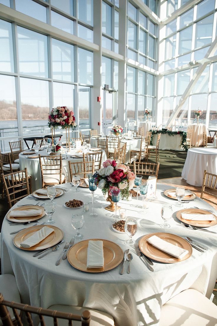 the tables are set with white linens and place settings, along with gold chargers