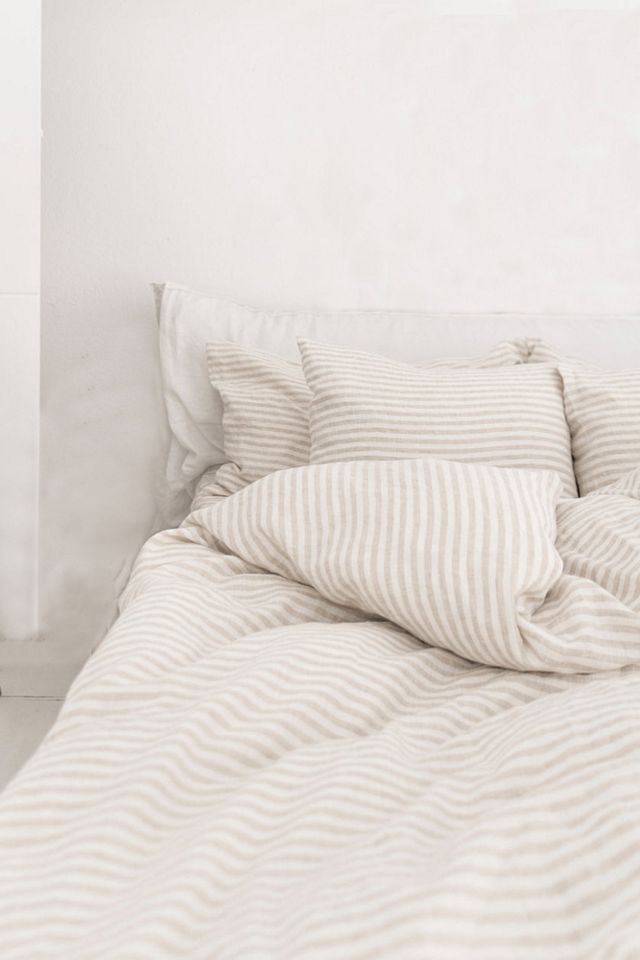 an unmade bed with two pillows on top of it in a white walled room