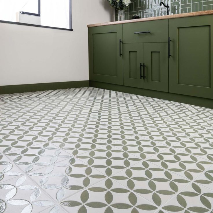 a kitchen with green cabinets and white flooring that has circles painted on the tiles