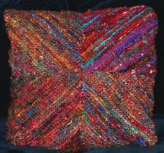 a multicolored knitted pillow on a black background