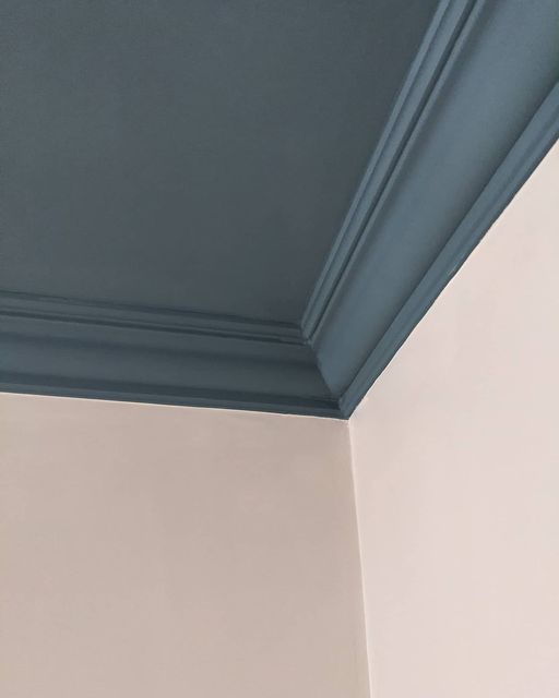 the corner of a room with a clock on it's wall and blue painted ceiling