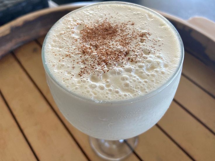 a drink in a glass sitting on top of a wooden table