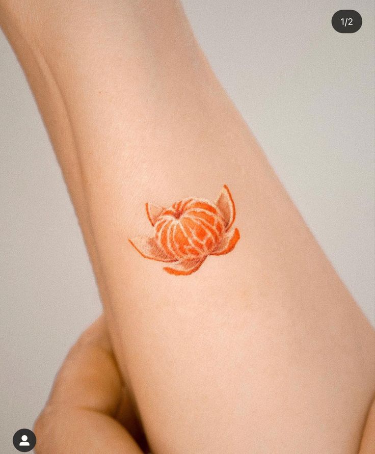 a woman's arm with an orange flower tattoo on the left side of her body