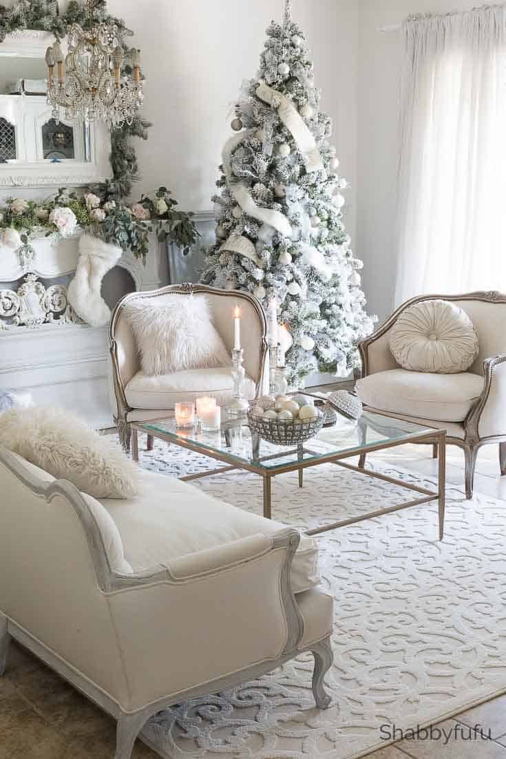 the living room is decorated for christmas with white furniture and trees in the background,