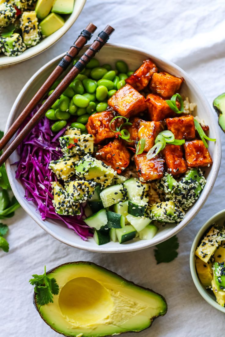 two bowls filled with vegetables and tofu next to chopsticks on a table