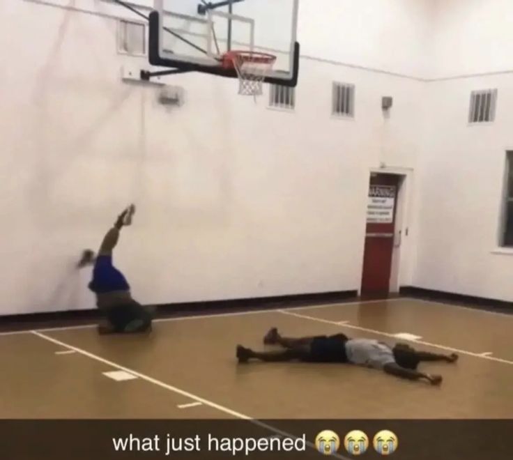 two men are playing basketball on an indoor court while another man is laying down in the middle of the floor