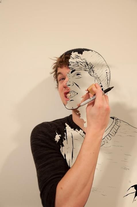 a young man holding a paintbrush to his face