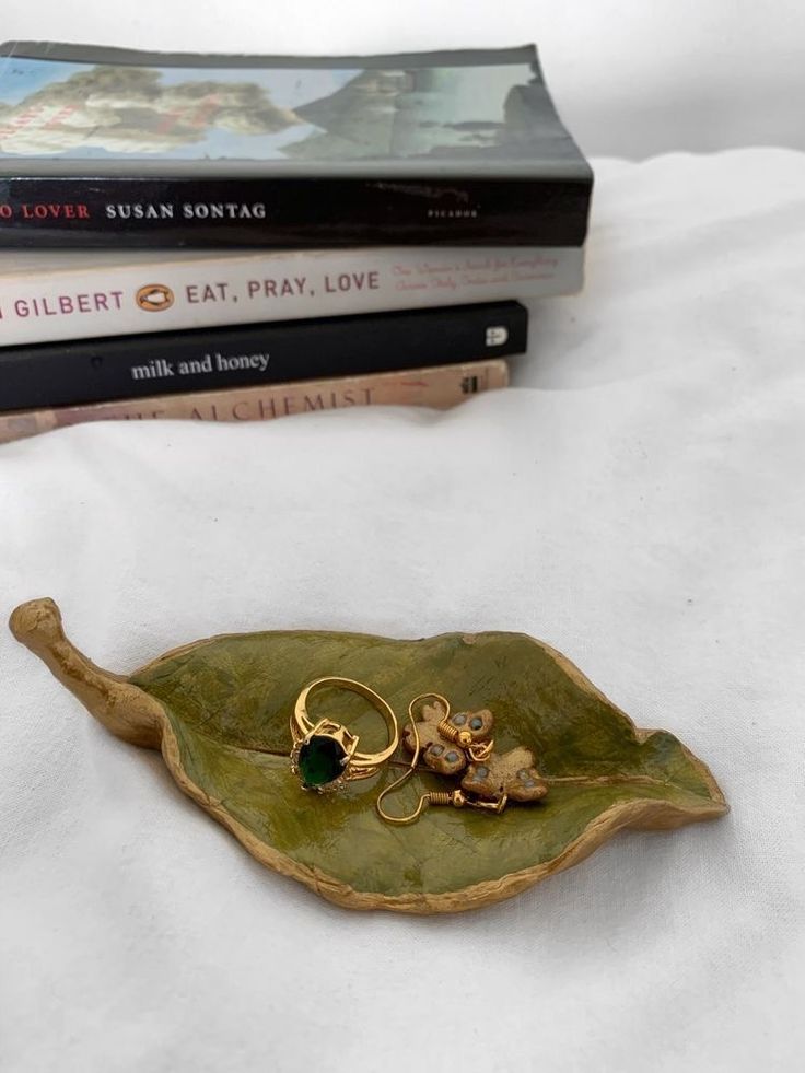 a pair of gold rings sitting on top of a green leaf next to two books