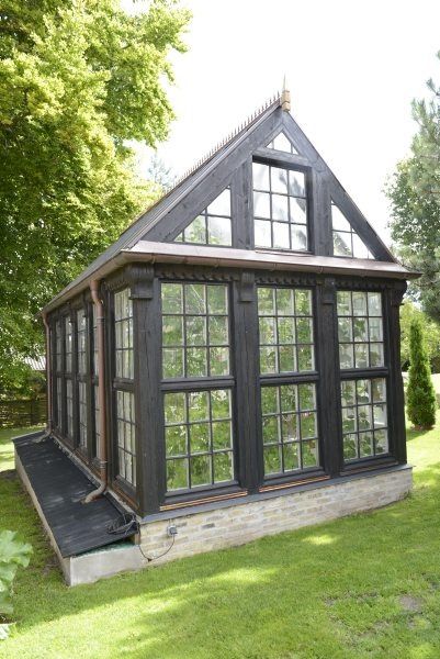 a small black house sitting on top of a lush green field