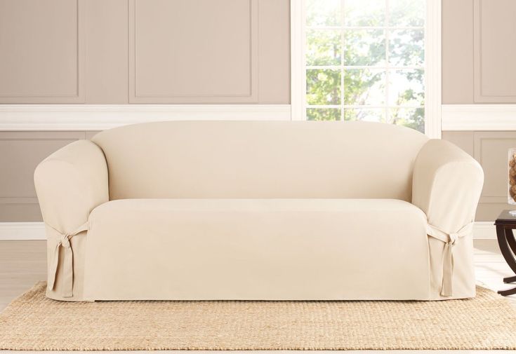 a living room with a couch covered in a white sofa cover next to a coffee table