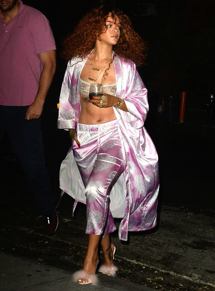 a woman in purple and white outfit walking down the street with a man behind her