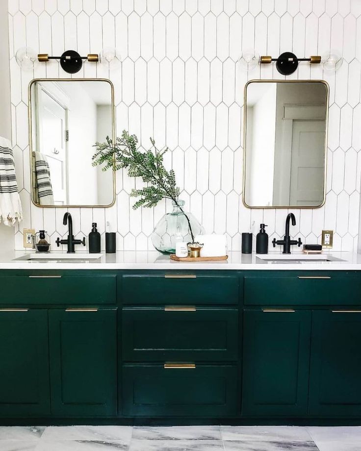 a bathroom with two sinks, mirrors and green cabinetry on the wall above them