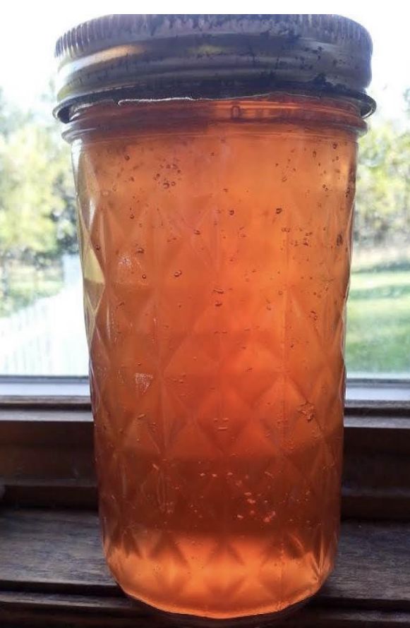 a jar filled with liquid sitting on top of a window sill