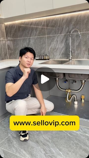 a man sitting on the ground in front of a sink with his hand under his chin