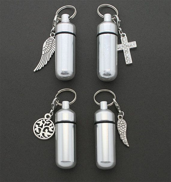 three bottles with charms attached to them on a black surface, one has a cross and the other is a keychain