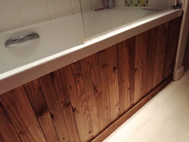 a bathroom with wood paneling and a bathtub next to it's door