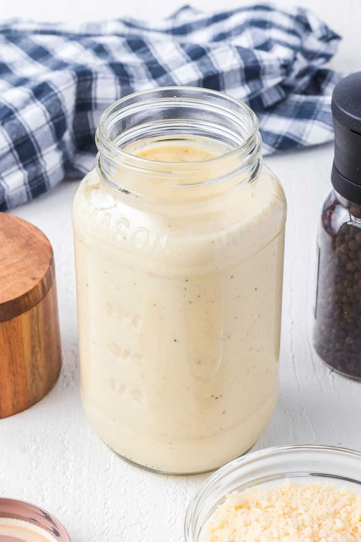 a jar filled with food sitting on top of a table next to two bowls and spoons