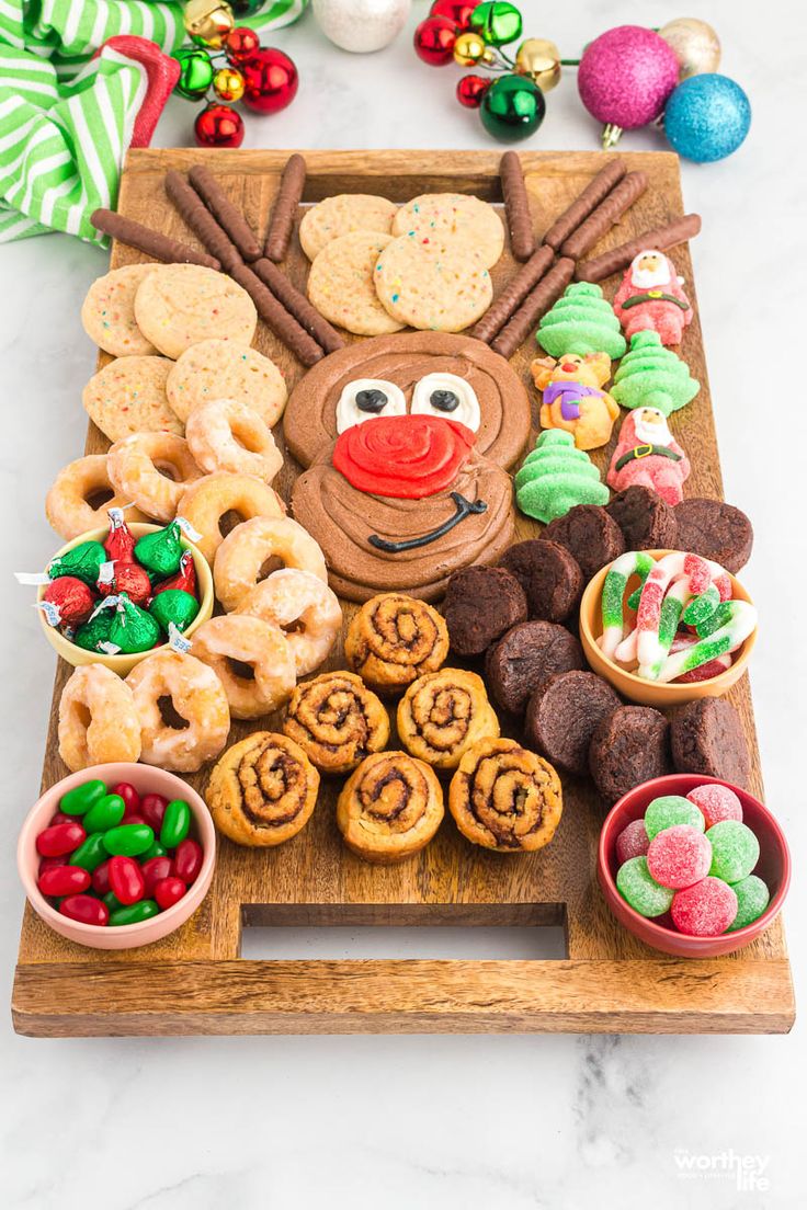 a wooden platter filled with cookies, pretzels and other holiday food items