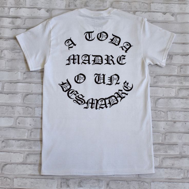 "\"A Toda Madre O Un Desmadre\", a motto we should all live by, we either win it all or lose everything. Font is in Spanish to represent our Hispanic Heritage. Screen printed design on the Back to remind the people walking behind you!" White Print Slogan Shirt For Streetwear, White Lettering T-shirt For Streetwear, White T-shirt With Lettering For Streetwear, Band Merch T-shirt With Lettering For Streetwear, Inspirational Graphic Print Top For Streetwear, Inspirational Cotton T-shirt For Streetwear, White Graphic Tee Shirt With Lettering, Lose Everything, People Walking