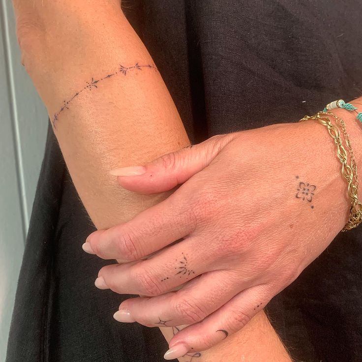 a woman's arm with tattoos on it and a gold chain around her wrist