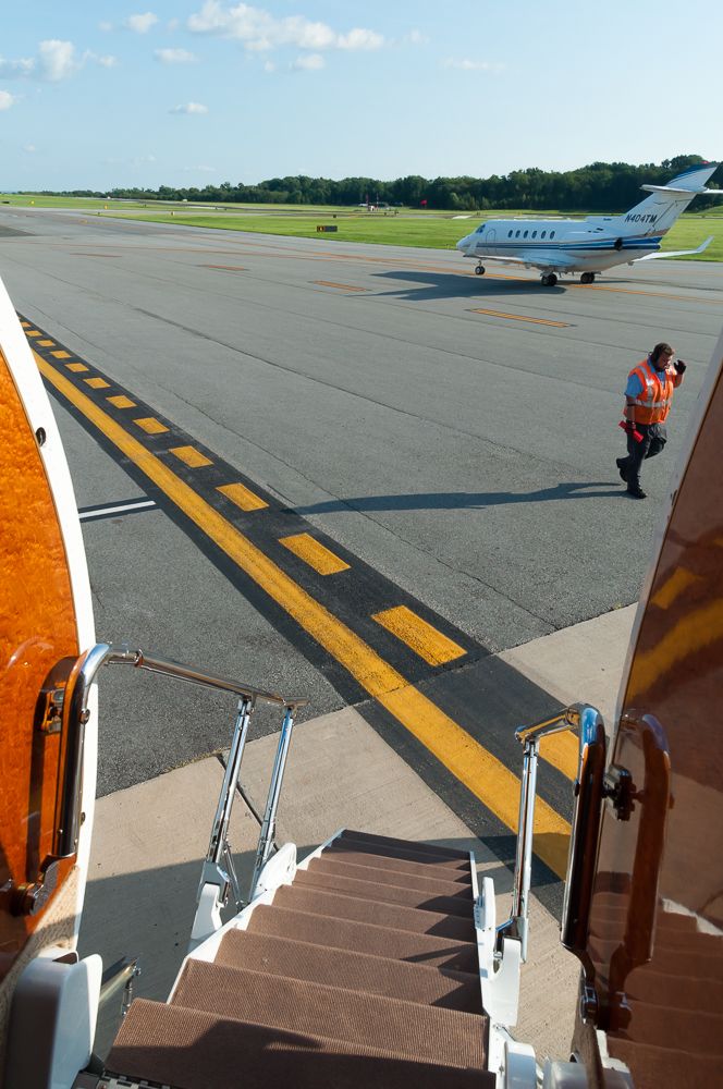 a man walking down the stairs to an airplane on the runway at an airport with another plane in the background