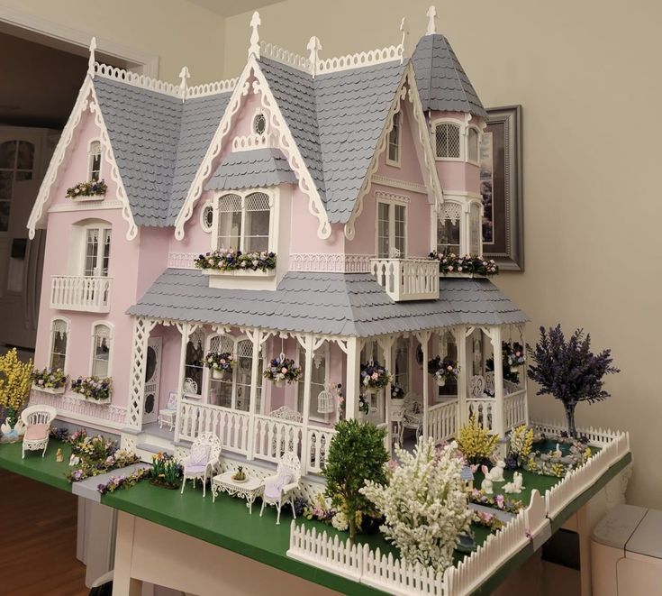 a large pink doll house sitting on top of a green table