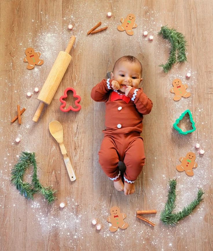 a baby is laying on the floor surrounded by ginger cookies and cookie cutters for christmas