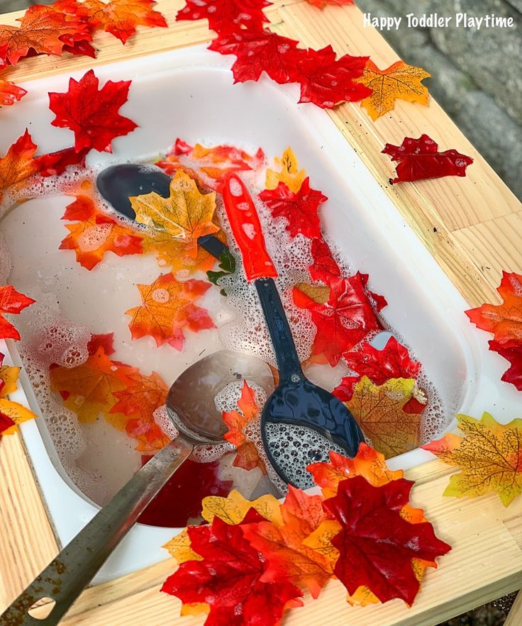 autumn leaves and spoons in a tray with water