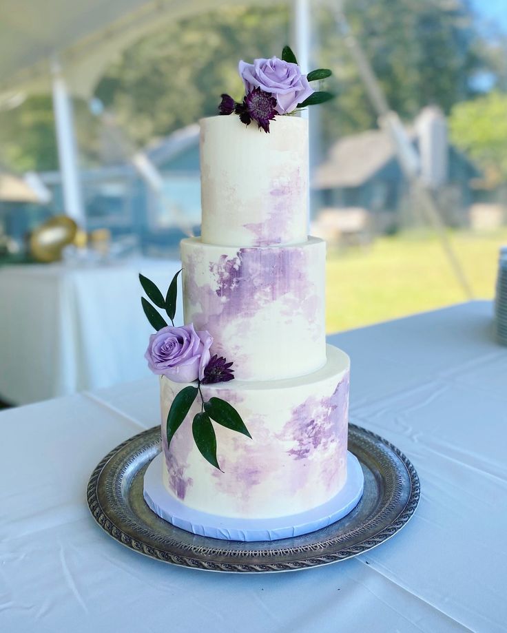 a three tiered cake with purple flowers on it