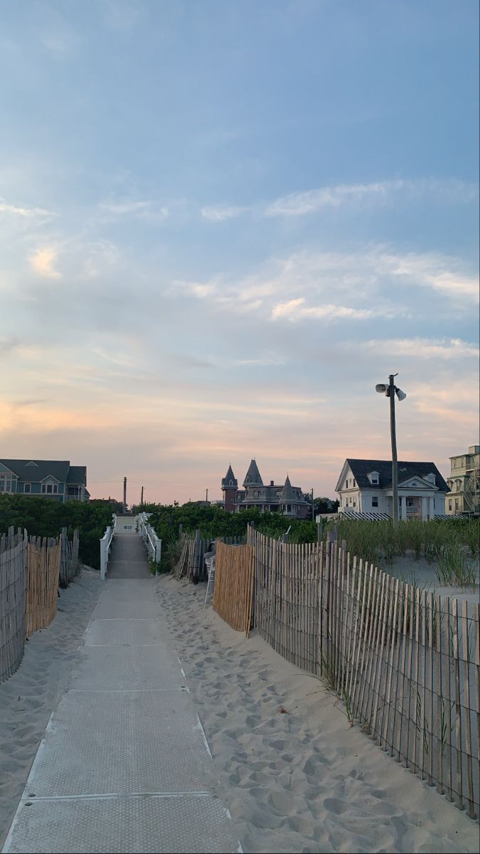 a walkway leading to the beach with houses in the background