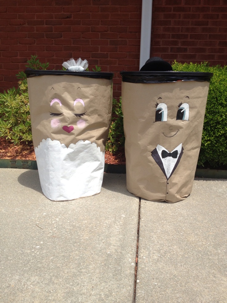 two trash bags decorated to look like people in tuxedo hats and bow ties