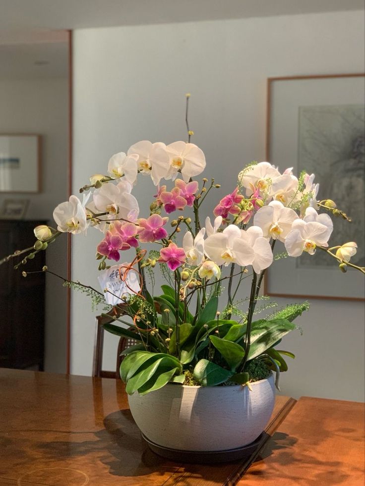 a vase filled with white and pink flowers on top of a wooden table