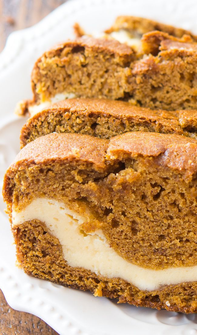 slices of pumpkin bread with cream cheese frosting on a white plate and wooden table