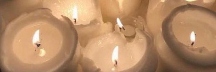 several white candles with one lit in the middle